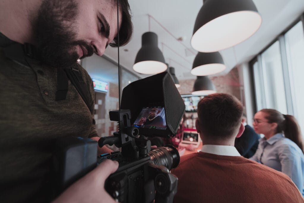 behind the scene. cameraman recording a group of young multiethnic business people working and communicating together in a creative office. selective focus